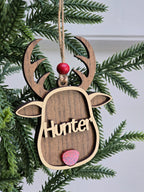 Wooden ornament shaped like a deer head with 'Hunter' engraved, hanging on a Christmas tree.