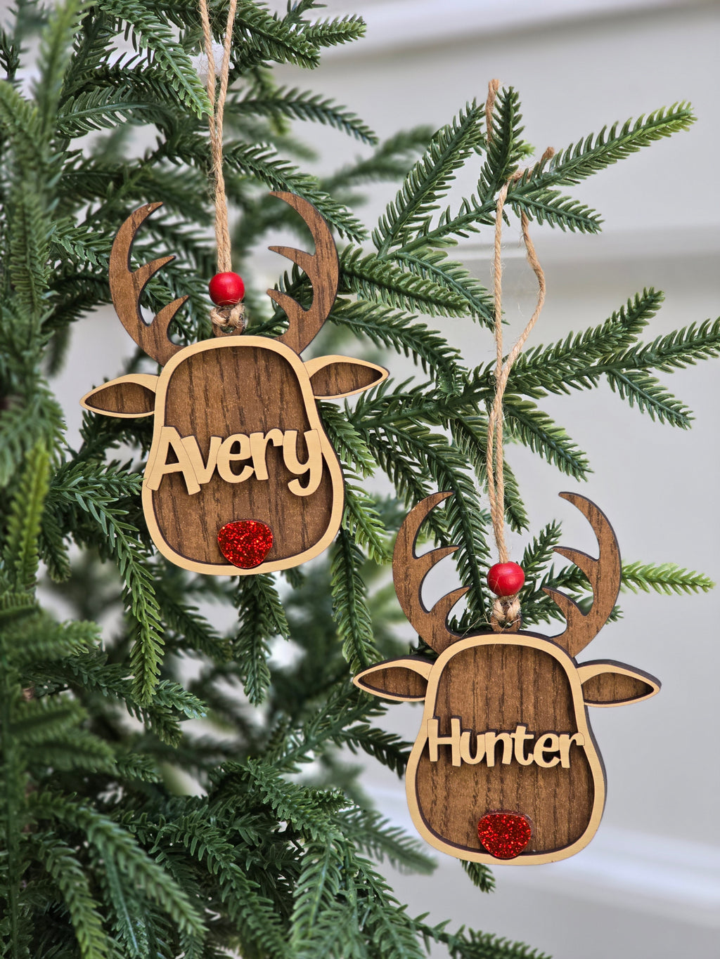 Wooden deer-shaped ornaments with names 'Avery' and 'Hunter' on a Christmas tree.