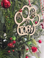 Wooden ornament with 'Toby' on a Christmas tree with red berries and green leaves.