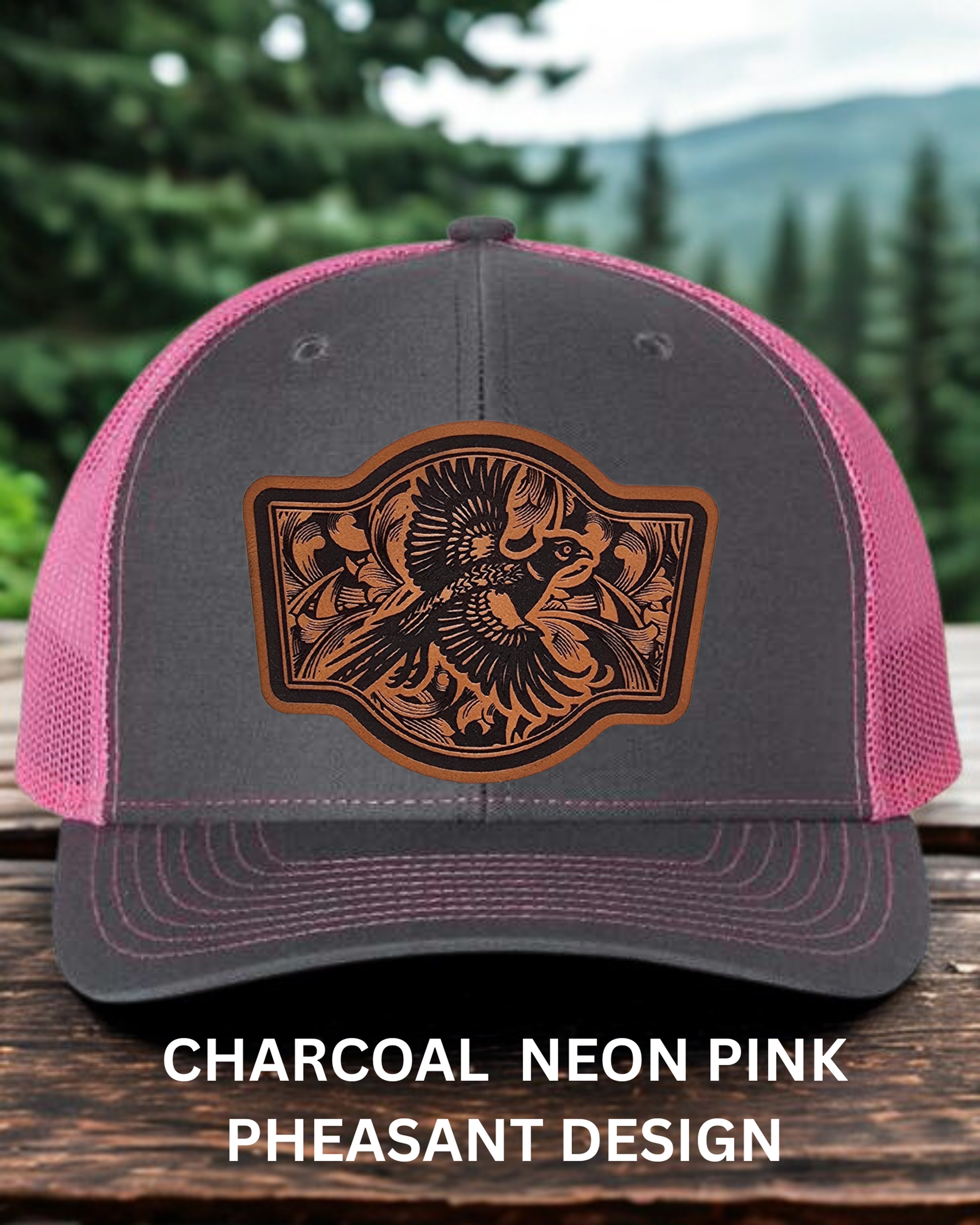 Gray and pink cap with a pheasant design on a wooden surface with a forest background