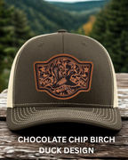 Green cap with brown duck design on a wooden surface with a forest background