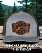 Gray and black cap with fish design on a wooden surface and forest background