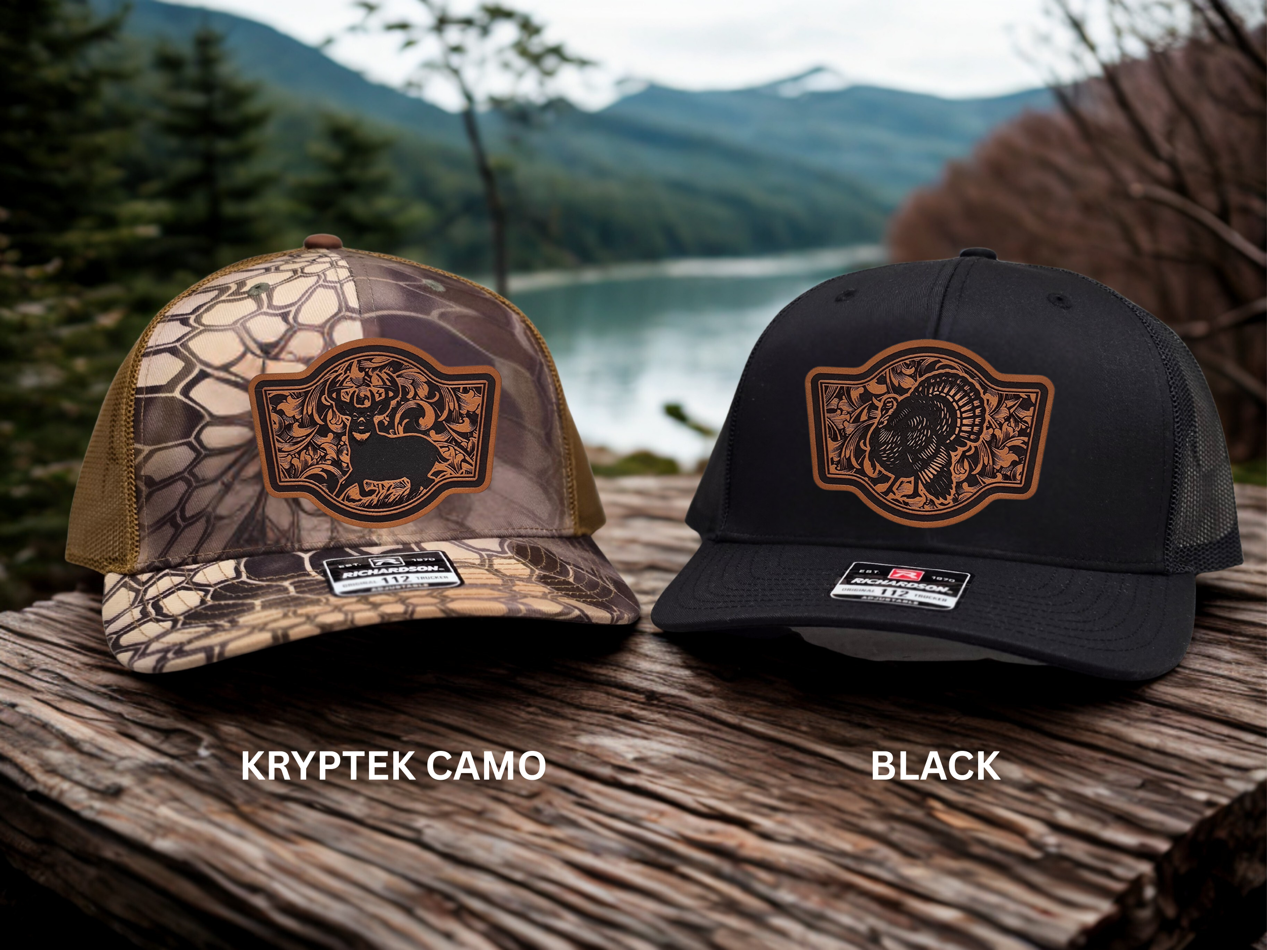Two hats, one Kryptek camo and one black, on a wooden surface with a scenic background.