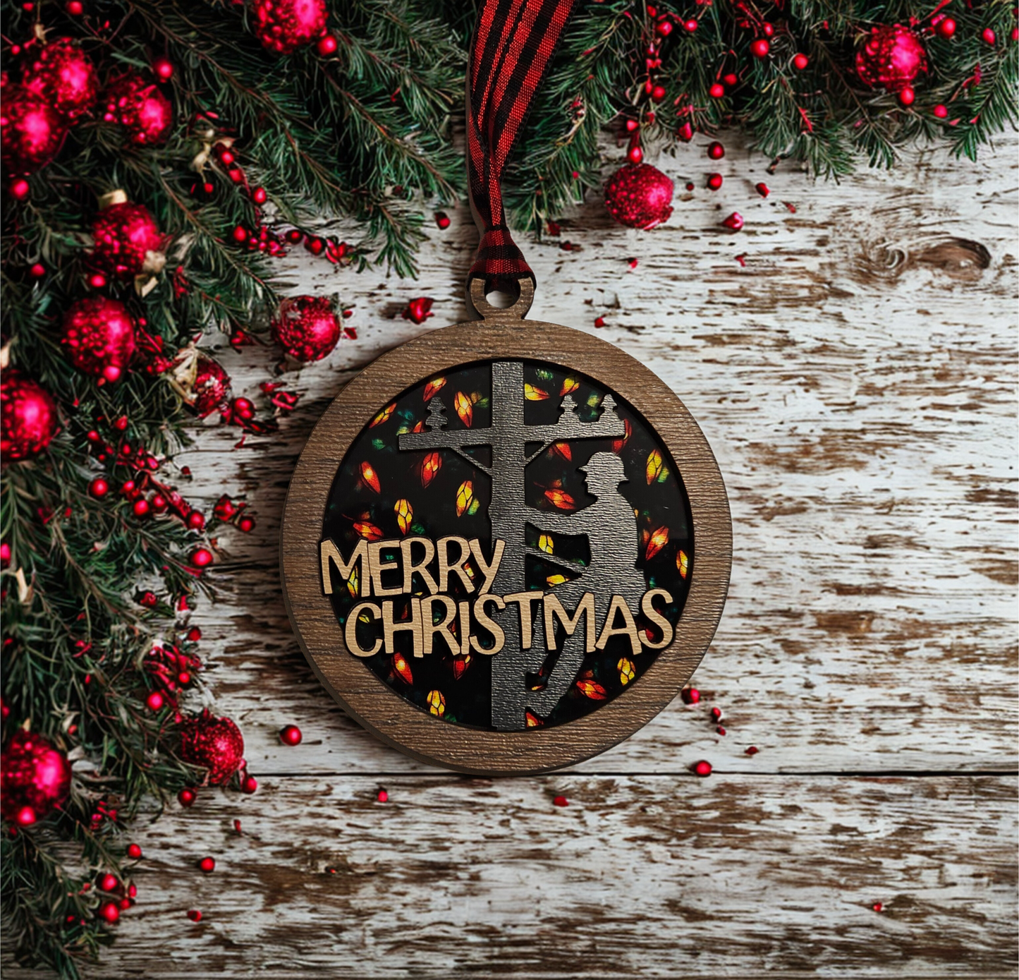 Wooden Christmas ornament with 'Merry Christmas' text and silhouette design, surrounded by festive decorations on a wooden surface.