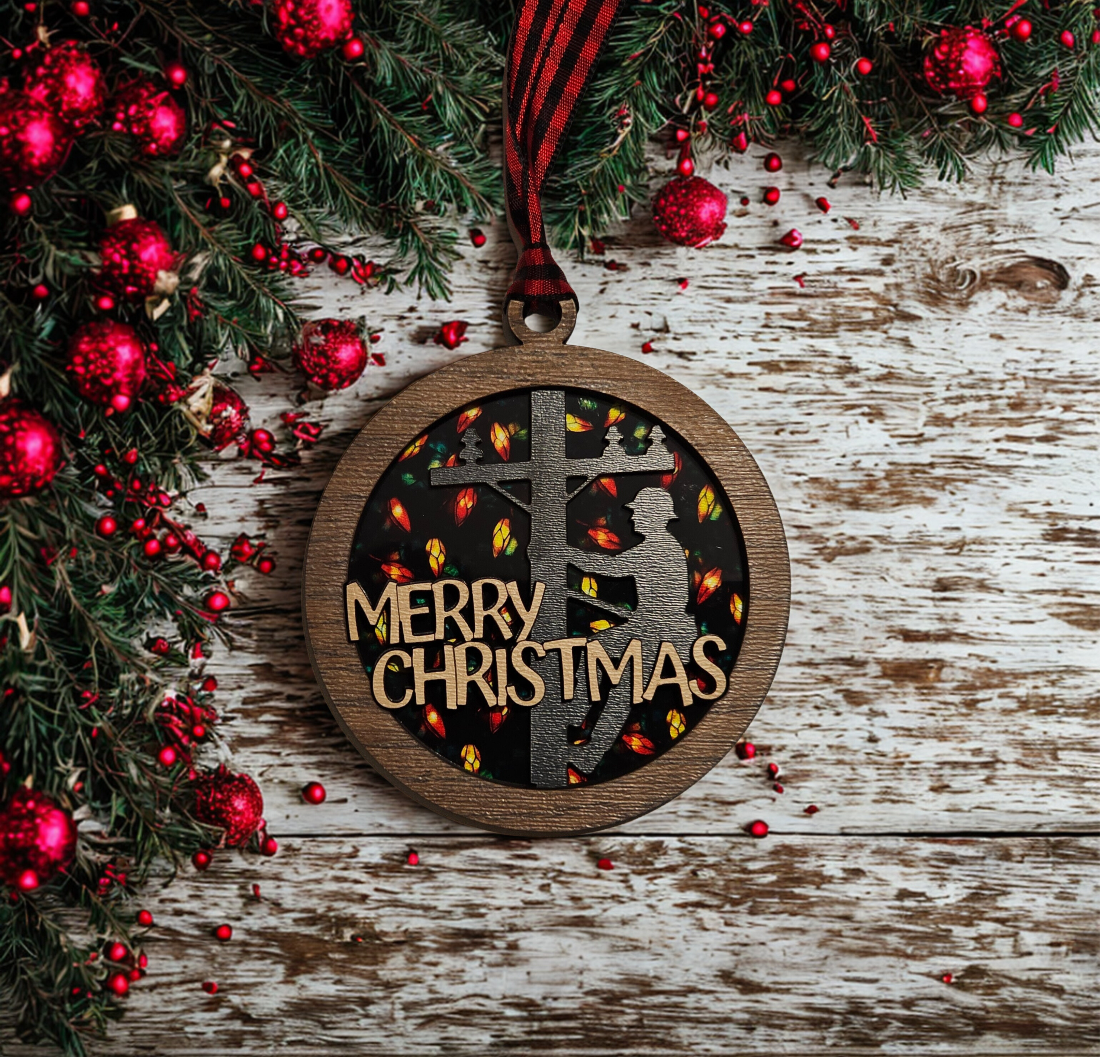 Wooden Christmas ornament with 'Merry Christmas' text and silhouette design, surrounded by festive decorations on a wooden surface.