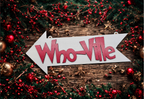 Decorative sign with 'Who-Ville' text surrounded by Christmas decorations on a wooden surface.