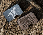 Two metal cards with engraved designs on a wooden surface