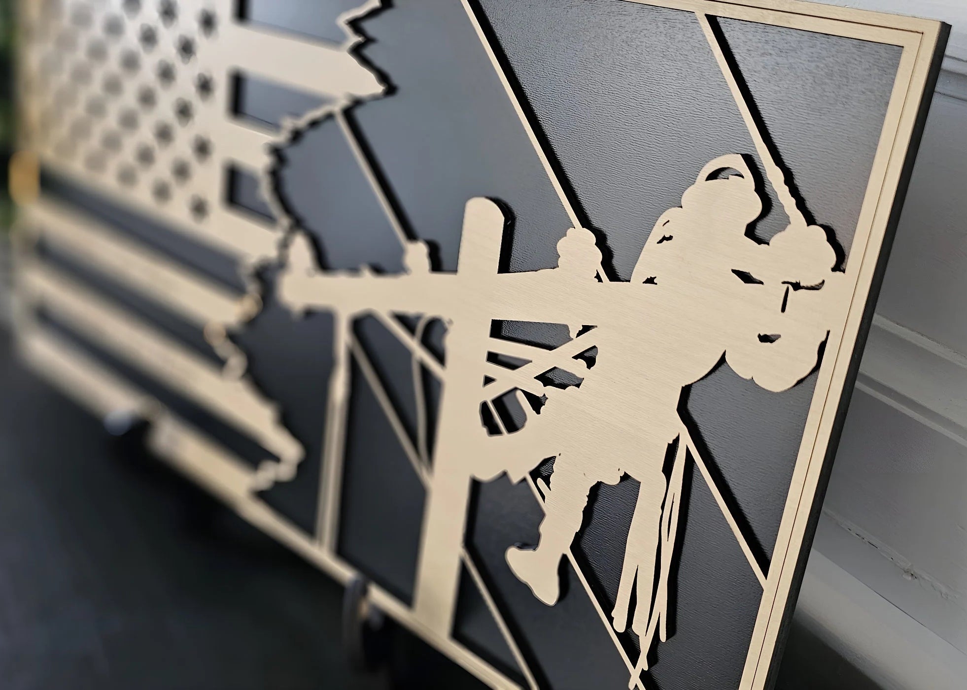 Angled close-up of personalized lineman flag plaque showing layered wood detail and black backing