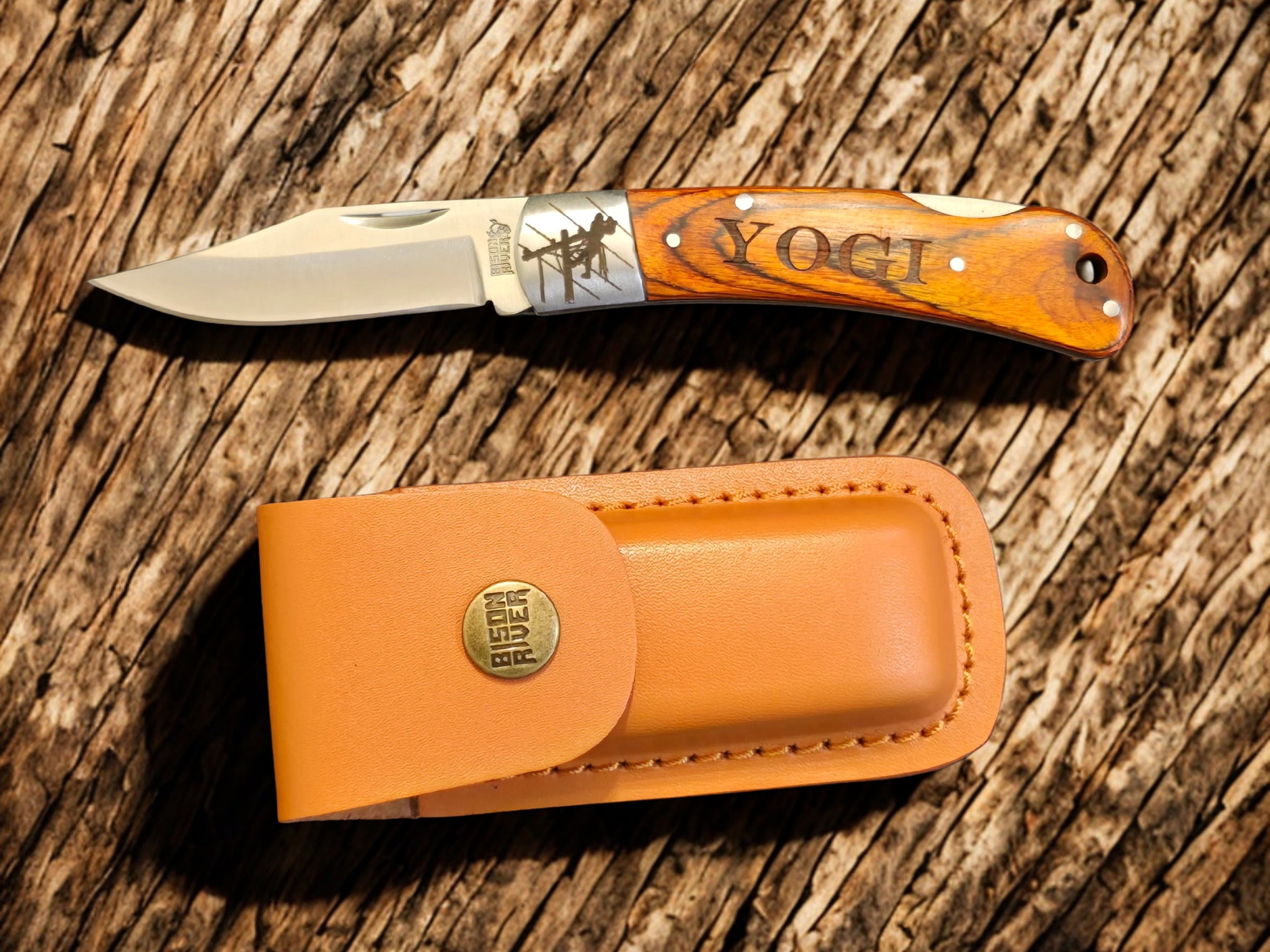 Lineman folding knife shown open with leather sheath on rustic wood background