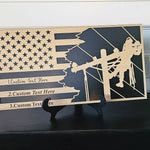 Personalized lineman flag plaque displayed on a black shelf with plant decor and included tabletop stand