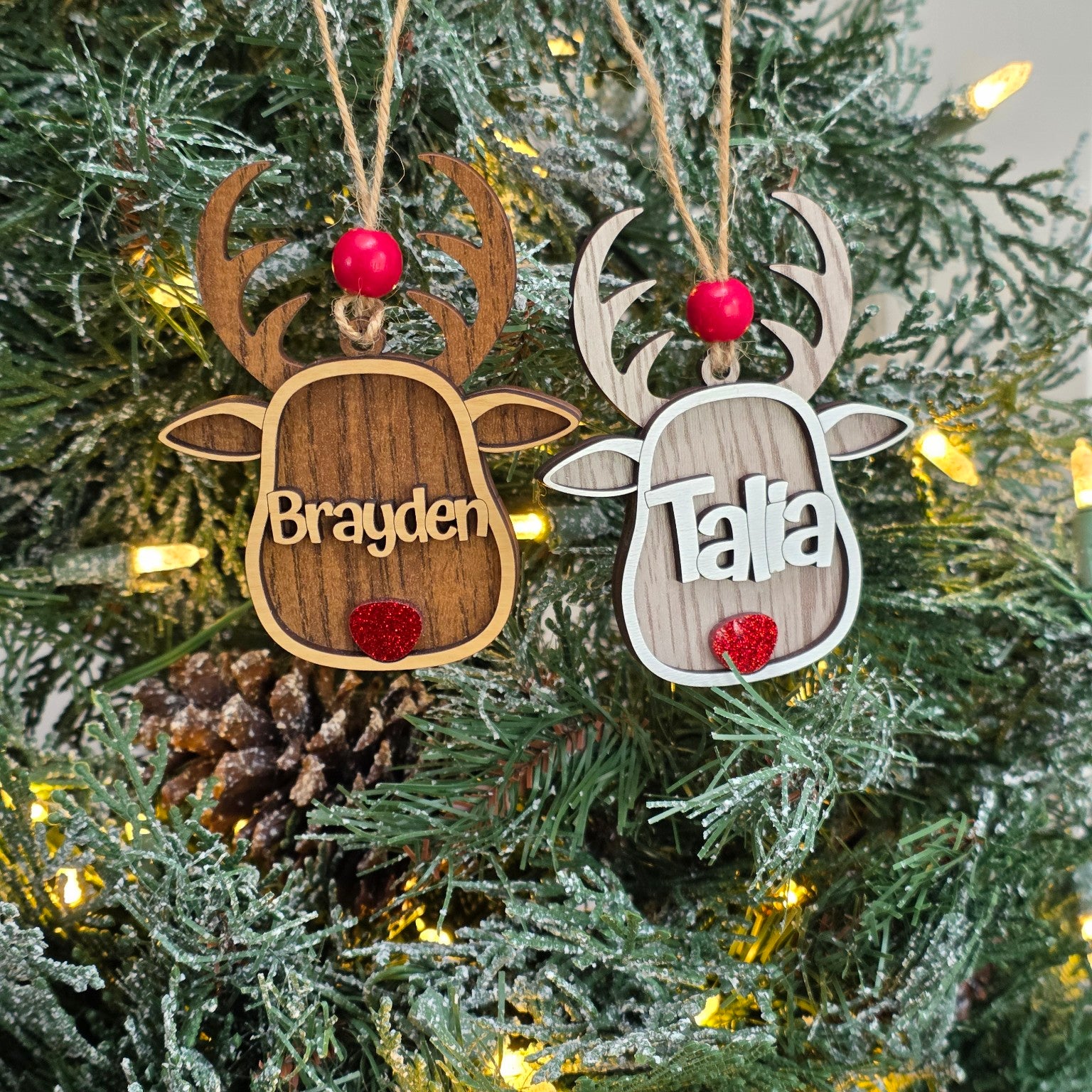 Personalized reindeer Christmas ornaments in Walnut and Whitewash hanging together on a lit Christmas tree