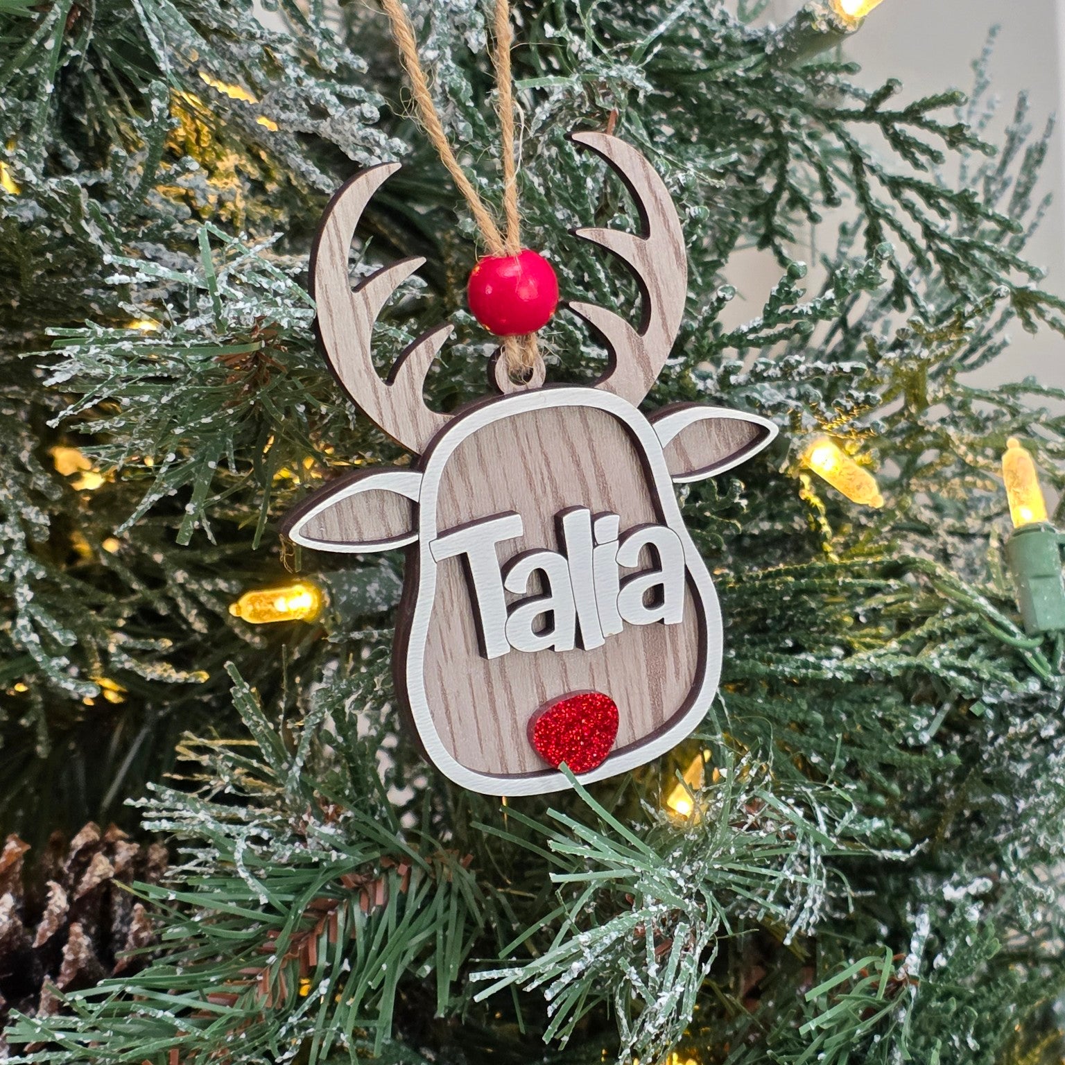 Whitewash personalized reindeer Christmas ornament with custom name hanging on a lit Christmas tree