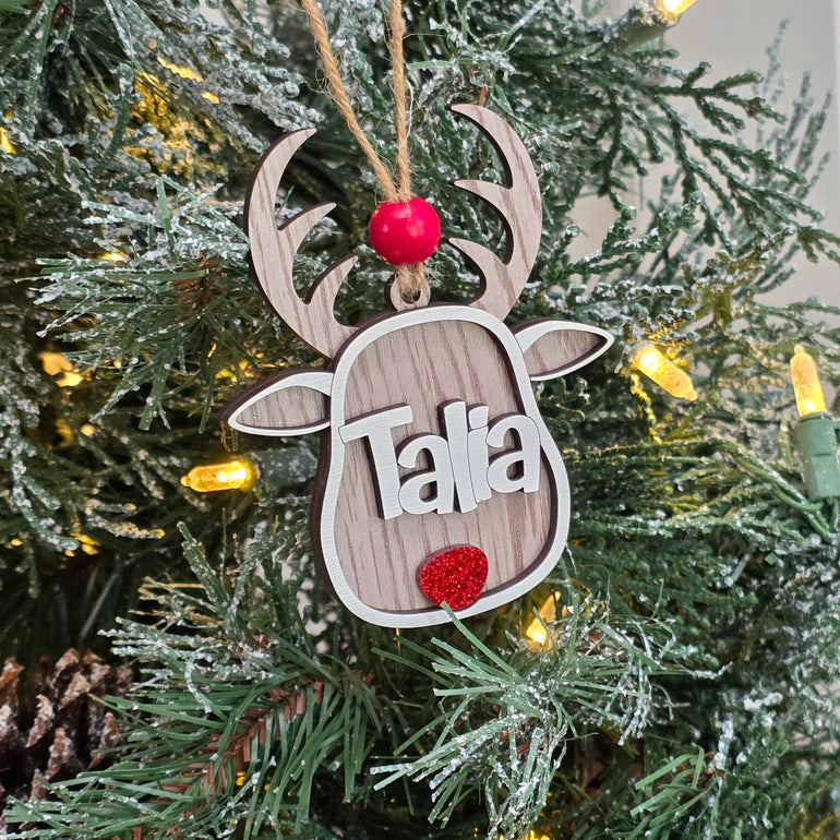 Whitewash personalized reindeer Christmas ornament with custom name hanging on a lit Christmas tree
