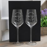 Pair of empty personalized wedding wine glasses displayed against a black background