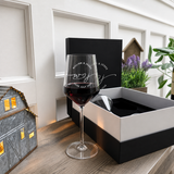Personalized wine glass filled with red wine beside the open two-glass presentation box